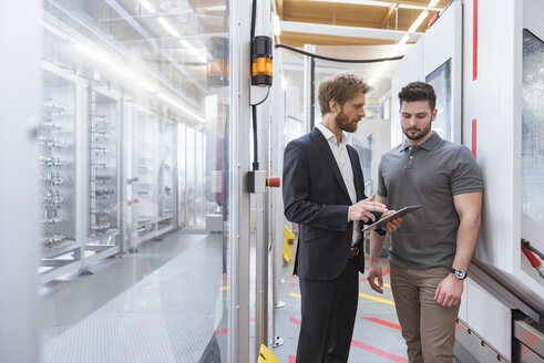 Zwei Männer mit Tablet sprechen an einer Maschine in einer modernen Fabrik - DIGF03871