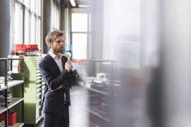 Businessman in modern factory staring - DIGF03880