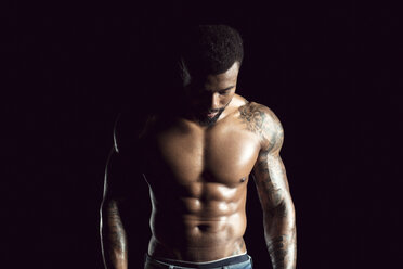 Tattooed physical athlete in front of black background - DAWF00605