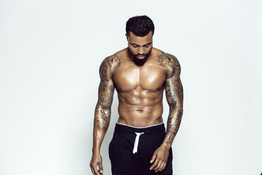 Tattooed physical athlete in front of light background - DAWF00611