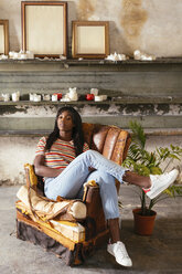 Porträt einer coolen jungen Frau, die auf einem alten Ledersessel in einem Loft sitzt - EBSF02296