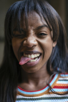 Porträt einer lachenden jungen Frau, die ihre Zunge herausstreckt - EBSF02302