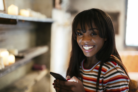 Porträt einer glücklichen jungen Frau mit Mobiltelefon, lizenzfreies Stockfoto