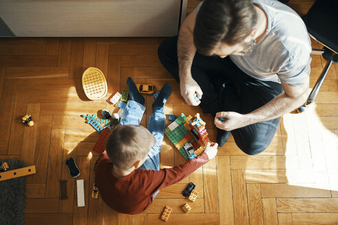 Vater und Sohn sitzen auf dem Boden und spielen zusammen mit Bauklötzen, Ansicht von oben - ZEDF01275