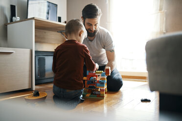 Vater und Sohn sitzen zu Hause auf dem Boden und spielen zusammen mit Bauklötzen - ZEDF01277