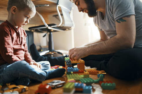 Father playing with building bricks on the floor while his sad little son watching him - ZEDF01280