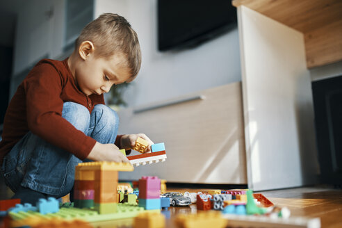 Little boy crouching on the floor at home playing with building bricks - ZEDF01283