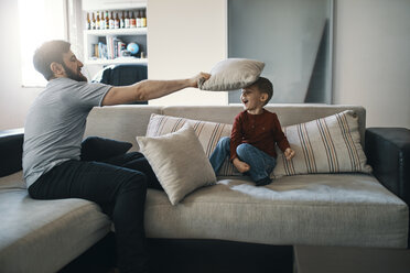 Vater und kleiner Sohn spielen zusammen auf der Couch im Wohnzimmer - ZEDF01289