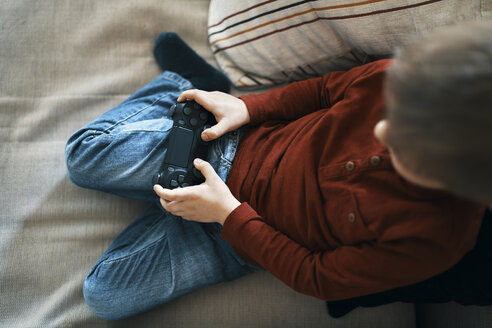 Kleiner Junge sitzt auf der Couch und spielt ein Computerspiel, Ansicht von oben - ZEDF01298