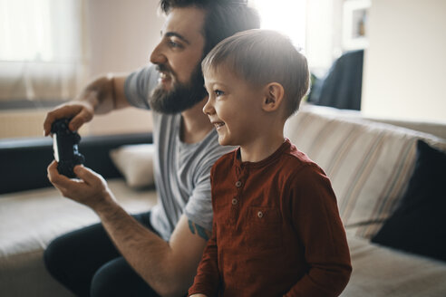 Happy little boy playing computer game with his father at home - ZEDF01306