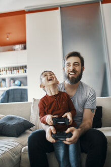 Vater und Sohn sitzen zusammen auf der Couch und spielen ein Computerspiel - ZEDF01307