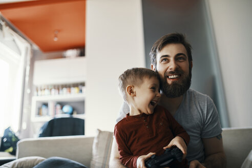 Vater und Sohn sitzen zusammen auf der Couch und spielen ein Computerspiel - ZEDF01308
