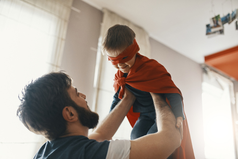 Father playing with his little son dressed up as a superhero stock photo