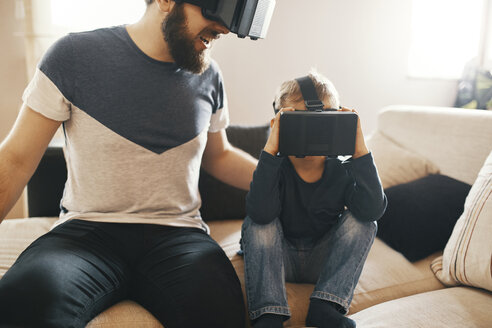 Father and little son wearing virtual reality glasses at home - ZEDF01326