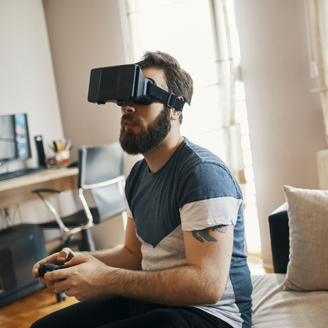 Man wearing virtual reality glasses at home playing computer game stock photo