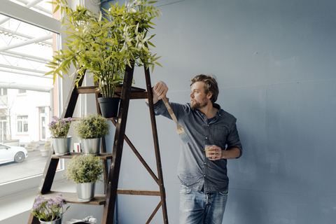 Mann mit Kaffeeglas und Pinsel schaut aus dem Fenster, lizenzfreies Stockfoto