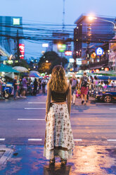 Thailand, Bangkok, young woman in the city standing on the street at night - AFVF00384