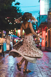 Thailand, Bangkok, junge Frau in der Stadt tanzen auf der Straße in der Nacht - AFVF00386