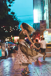 Thailand, Bangkok, junge Frau in der Stadt tanzen auf der Straße in der Nacht - AFVF00387
