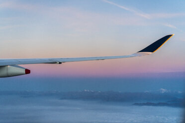 Flügel eines Flugzeugs über den Wolken mit Bergen im Hintergrund - AFVF00394