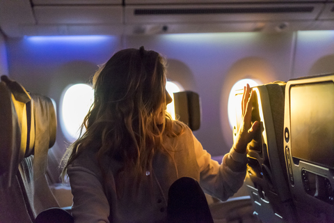 Junge Frau im Flugzeug bei Sonnenaufgang, lizenzfreies Stockfoto