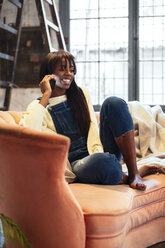 Lächelnde Frau am Telefon, die zu Hause auf der Couch sitzt - EBSF02311