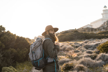 Italien, Sardinien, Wanderer mit Hut und Rucksack beobachtet etwas - AFVF00401