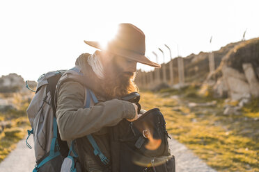 Italien, Sardinien, bärtiger Wanderer mit Hut und Rucksack im Gegenlicht - AFVF00403