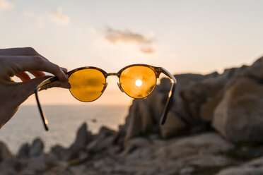 Männerhand hält Sonnenbrille vor Abendsonne, Nahaufnahme - AFVF00411