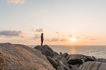 Italien, Sardinien, Mann steht bei Sonnenuntergang auf einem Felsen und betrachtet die Aussicht - AFVF00413