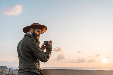 Italien, Sardinien, Mann beim Fotografieren mit Kamera bei Sonnenuntergang - AFVF00414