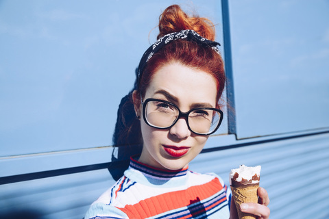 Portrait of redhead young woman holding ice cream cone against mini van stock photo