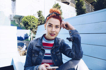 Portrait of redhead young woman using mobile phone while sitting on bench - MASF01363