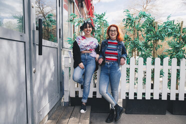 Porträt von Hipster-Freundinnen, die am Zaun eines Gebäudes stehen - MASF01368