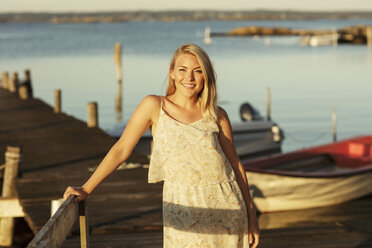 Porträt einer lächelnden blonden Frau, die an der Reling eines Bootsstegs steht - MASF01404