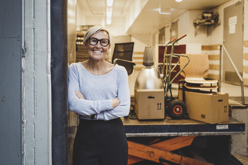 Portrait of smiling mature businesswoman standing arms crossed in new office - MASF01456