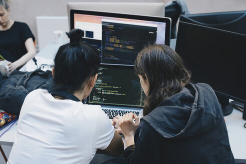 Blick über die Schulter von Computerprogrammierern, die einen Laptop im Büro benutzen - MASF01475