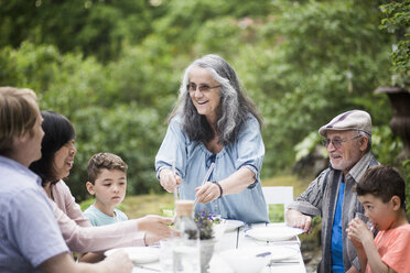 Mehrgenerationenfamilie am Tisch im Hinterhof - MASF01483