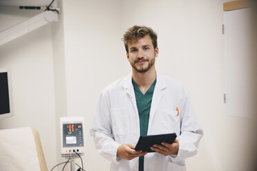 Porträt eines selbstbewussten männlichen Arztes, der mit einem digitalen Tablet im Krankenhaus steht - MASF01487