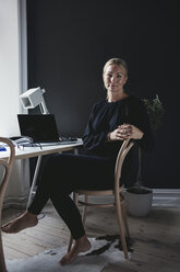 Portrait of businesswoman sitting on chair by desk in home office - MASF01501