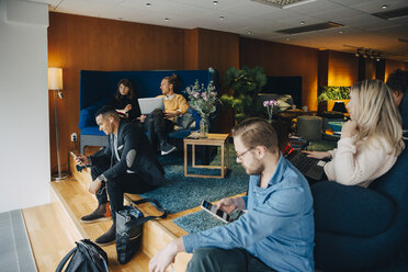 Multi-ethnic business coworkers using technologies sitting at office cafeteria - MASF01507