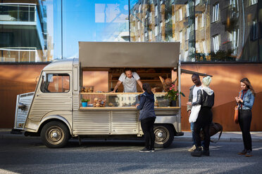 Multi-ethnic customers buying from owner in food truck against building - MASF01521