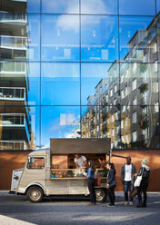Multiethnische Kunden, die in einem Imbisswagen vor einem städtischen Gebäude Lebensmittel vom Besitzer kaufen - MASF01522