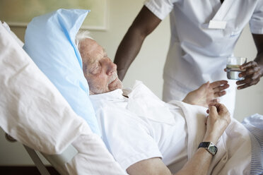 Midsection of male nurse giving drinking water to senior man in hospital ward - MASF01538