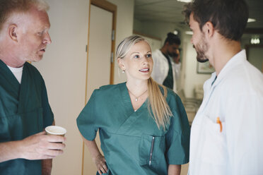 Medical colleagues discussing while standing in corridor at hospital - MASF01551