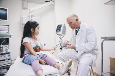 Mature doctor talking with girl while preparing pulse oxymeter at hospital - MASF01559