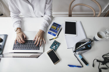 Midsection of businesswoman using laptop on table at home office - MASF01583