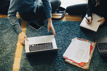 Midsection von Geschäftskollegen sitzen auf Teppich mit Dokumenten und Laptop in Büro-Cafeteria - MASF01589