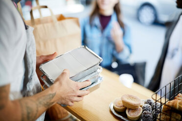 Mittelteil eines Verkäufers, der verpackte Lebensmittel zum Mitnehmen für Kunden an einem Verpflegungsstand hält - MASF01607