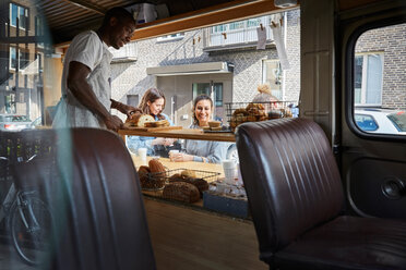 Mittlerer Erwachsener Verkäufer, der frisches Brot an Kunden im Imbisswagen verkauft - MASF01610